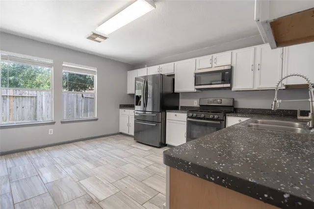 a kitchen with stainless steel appliances granite countertop a sink a stove a microwave and cabinets