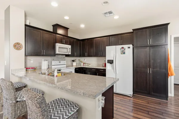 a kitchen with stainless steel appliances granite countertop a refrigerator a sink a stove a microwave and wooden cabinets