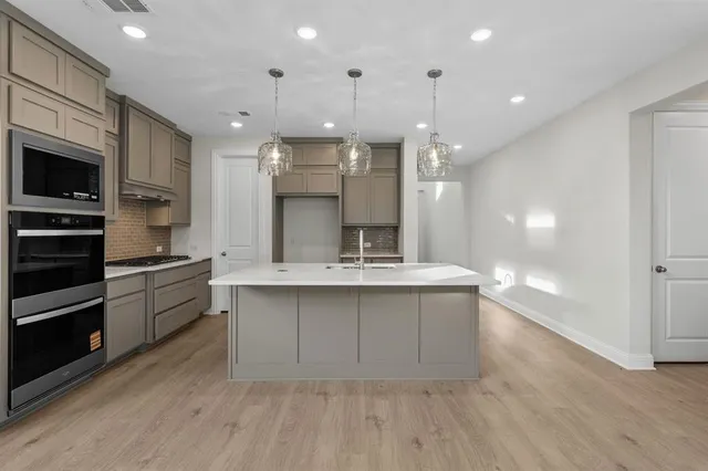 a large kitchen with granite countertop a large counter top stainless steel appliances and cabinets