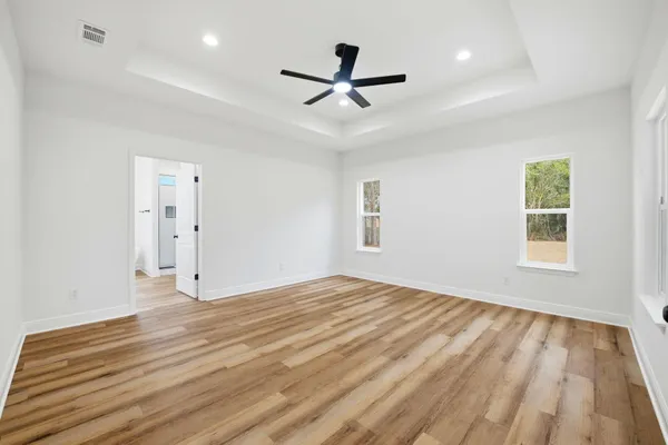 a view of empty room with wooden floor and fan