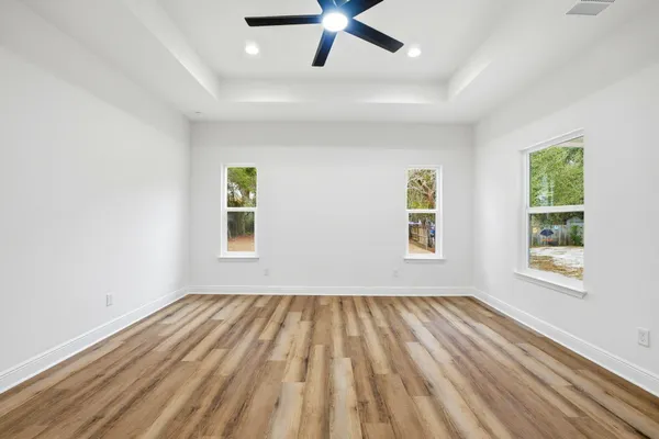 a view of empty room with wooden floor and fan