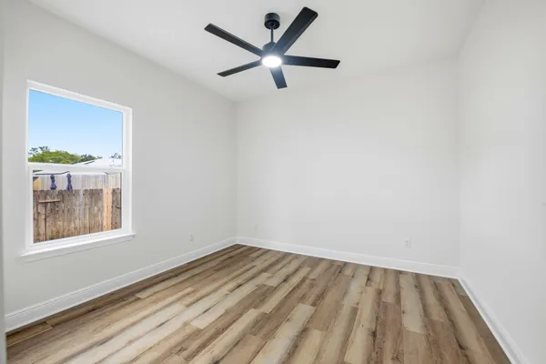 an empty room with a window and a fan