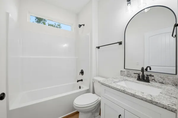a bathroom with a granite countertop sink a toilet and a mirror