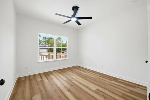 a view of empty room with wooden floor and fan