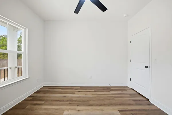 a view of an empty room with wooden floor and window