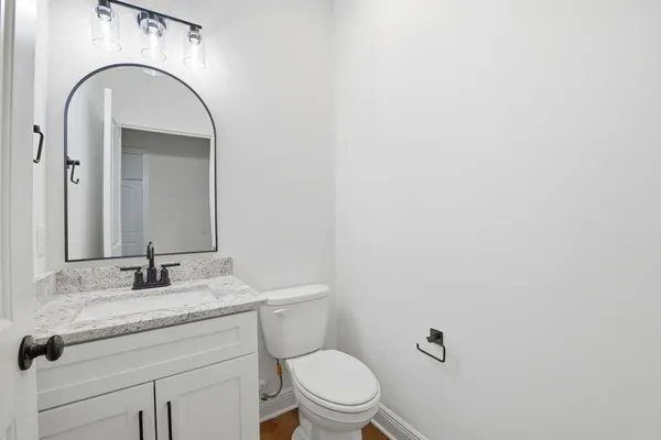 a bathroom with a granite countertop toilet a sink and mirror