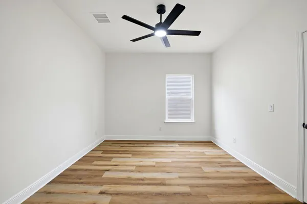 an empty room with a ceiling fan and wooden floor