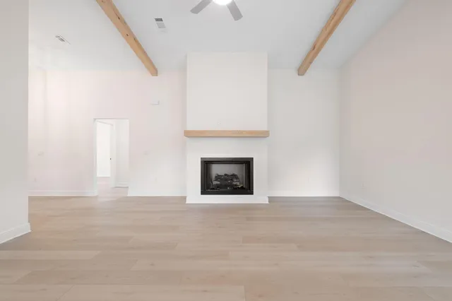 a view of an empty room with wooden floor and a fireplace