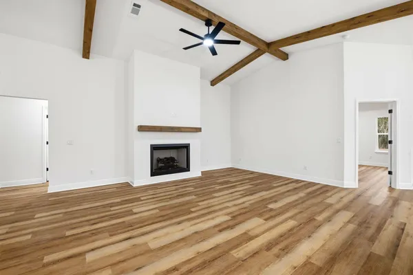 a view of empty room with fan and wooden floor