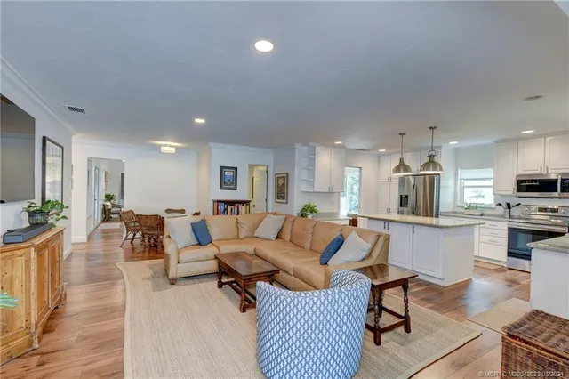 a living room with furniture kitchen view and a wooden floor