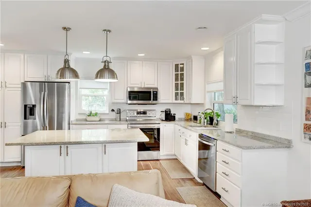 a kitchen with stainless steel appliances granite countertop a refrigerator sink and white cabinets