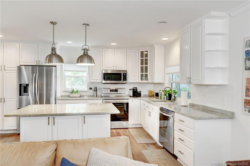 5 Banyan Road Stuart, FL 34996 - Photo 13 of 49 a kitchen with stainless steel appliances granite countertop a refrigerator sink and white cabinets