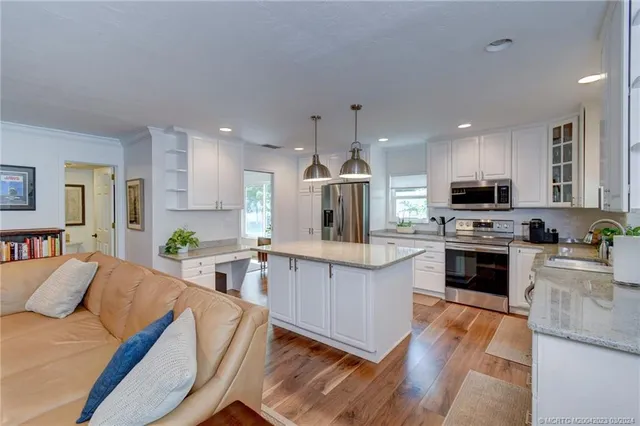 a kitchen with stainless steel appliances granite countertop a stove top oven a sink dishwasher and a refrigerator with wooden floor