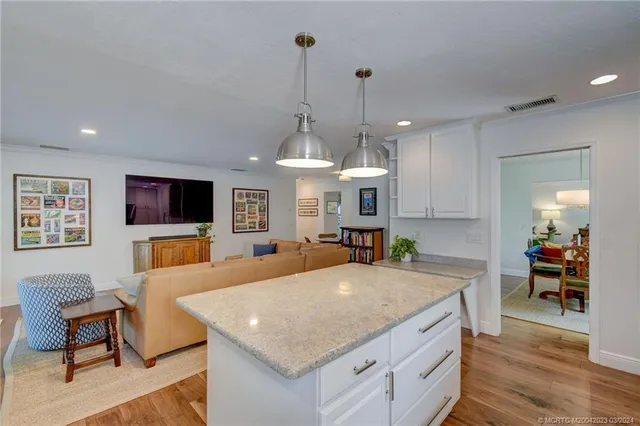 a view of a kitchen with kitchen island stainless steel appliances a table and chairs in it