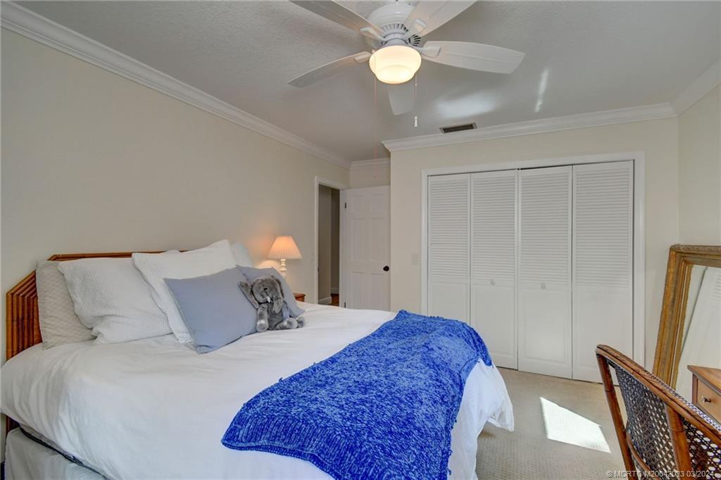 5 Banyan Road Stuart, FL 34996 - Photo 23 of 49 a bedroom with a bed and a flat tv screen on a dresser