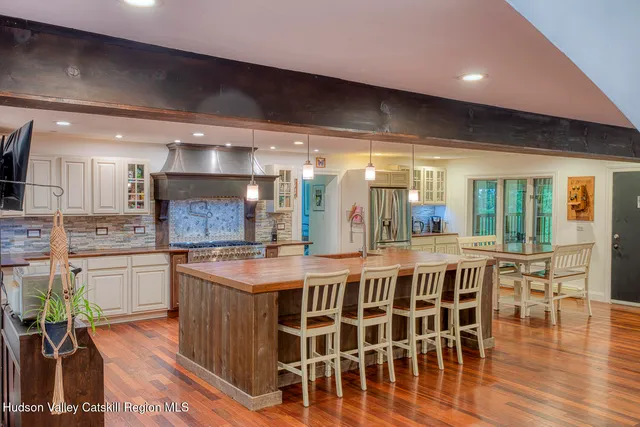 a kitchen with stainless steel appliances granite countertop a kitchen island a stove and a dining table with wooden floor