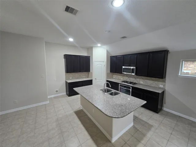 a kitchen with granite countertop a sink a stove and cabinets