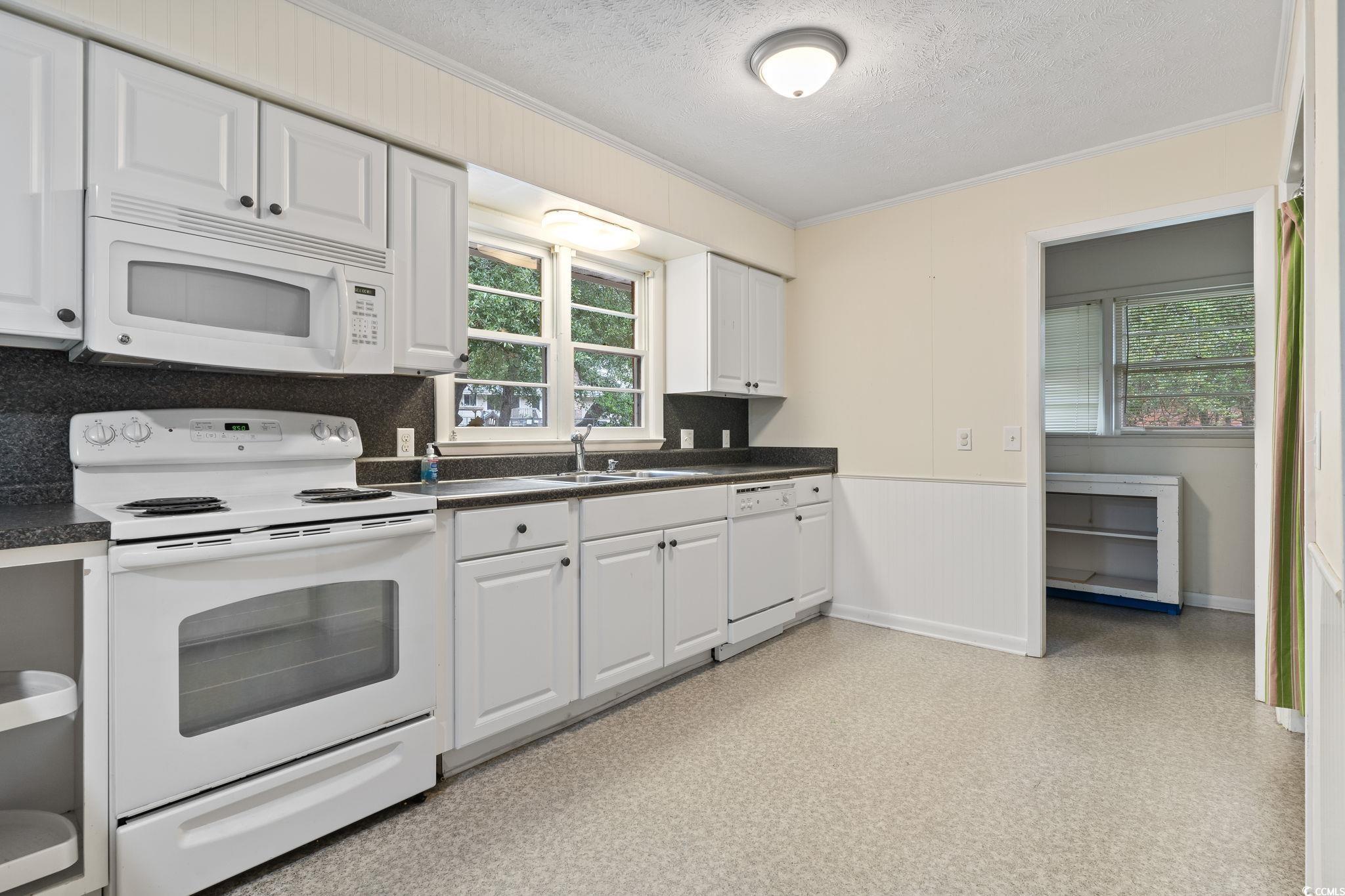 Kitchen with a textured ceiling, sink, white appli