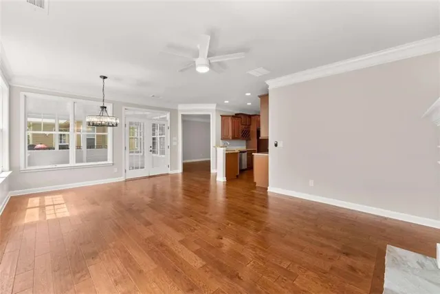 a view of empty room with wooden floor and kitchen view