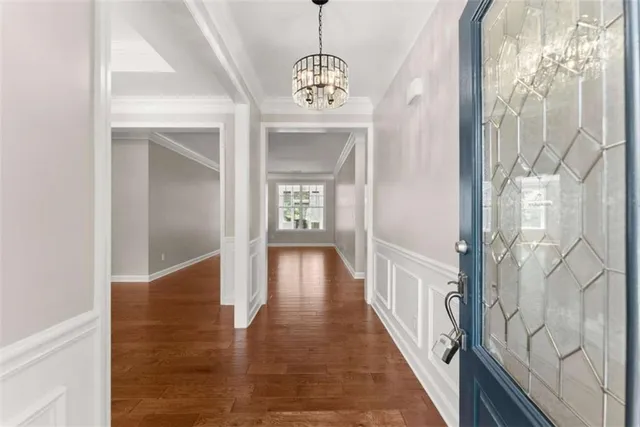 a view of a hallway with wooden floor and a chandelier