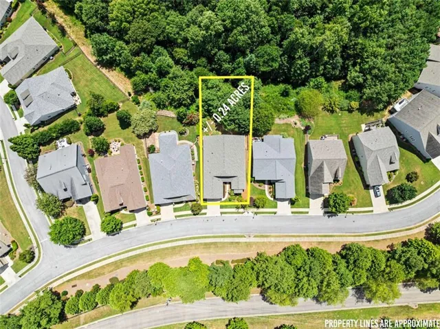 an aerial view of a residential houses with outdoor space and trees