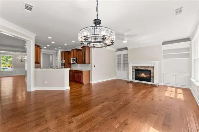a view of a room with wooden floor a kitchen a refrigerator and a fireplace
