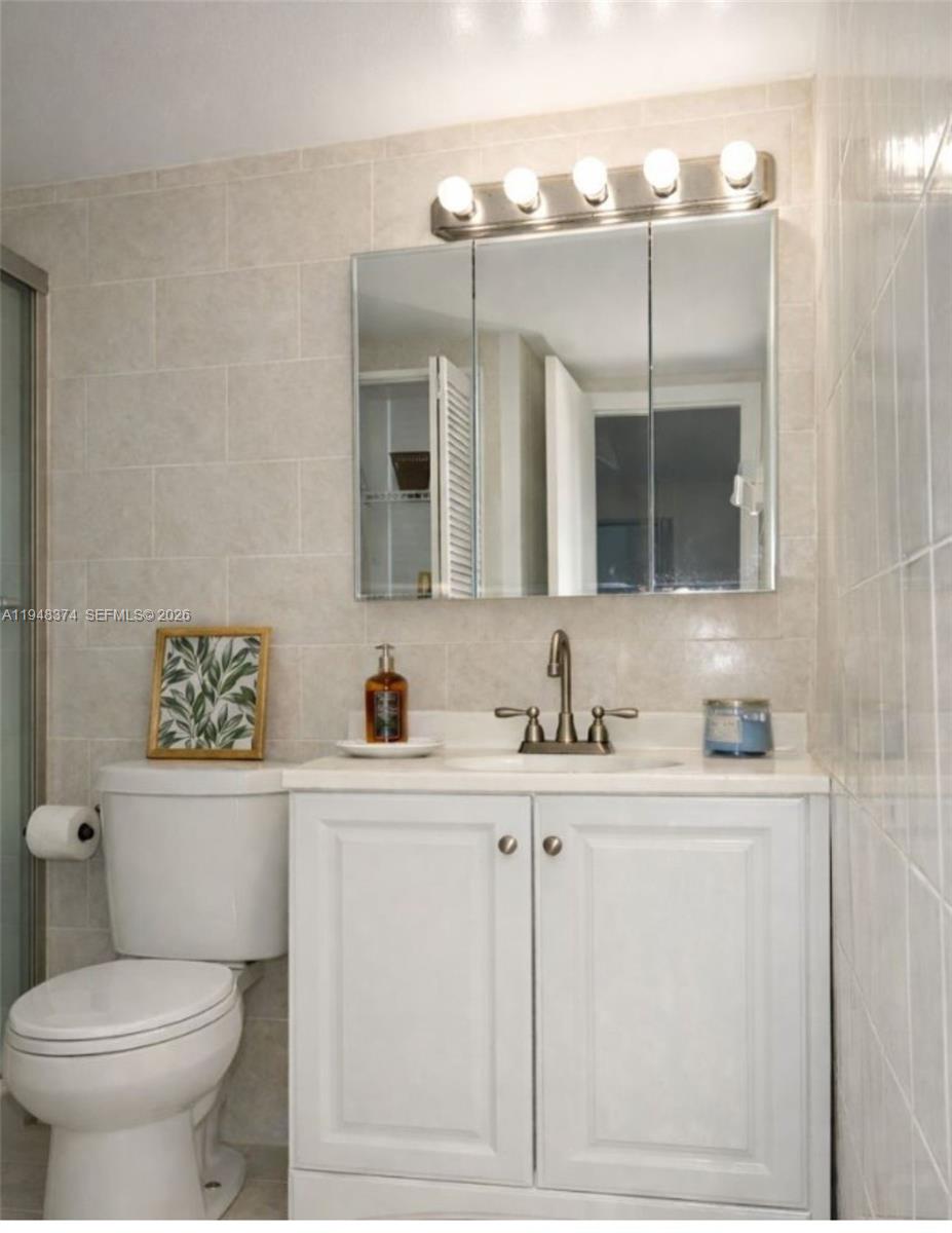 4845 Northwest 7th Street, Unit 1065 Miami, FL 33126 - Photo 2 of 6 a bathroom with a sink a toilet and mirror