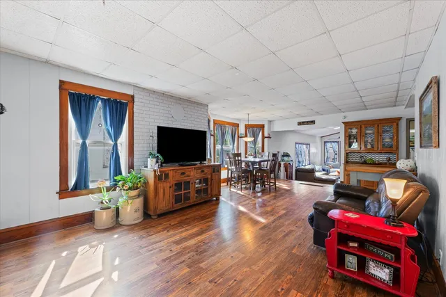 a living room with furniture a flat screen tv and a refrigerator