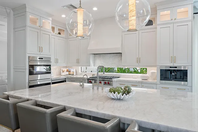a kitchen with stainless steel appliances kitchen island granite countertop a sink a stove and white cabinets
