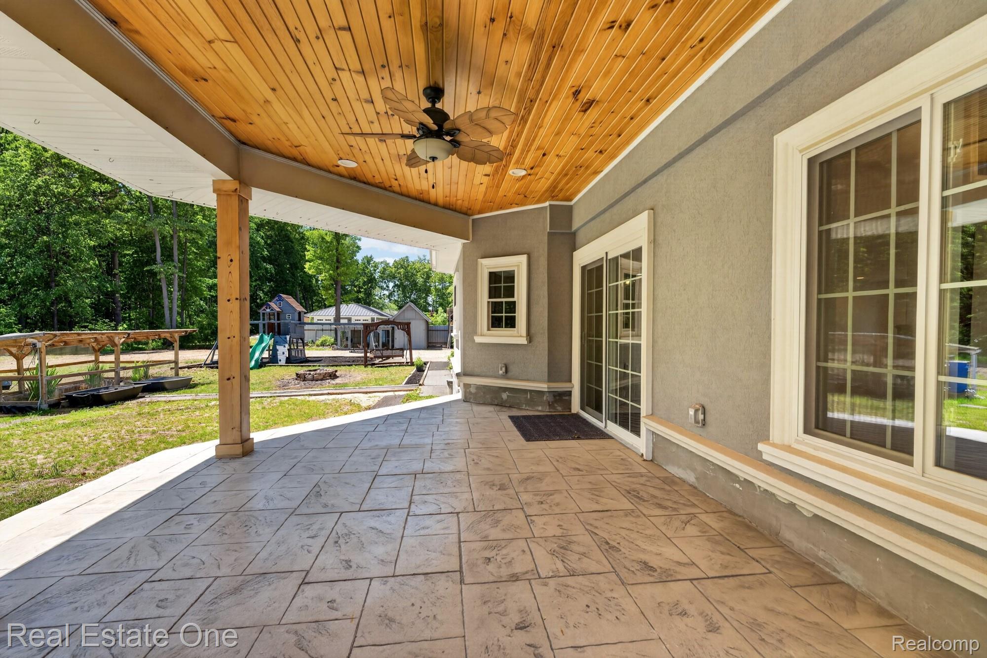 26987 Crawford Road Romulus, MI 48174 - Photo 44 of 51 Expansive covered patio featuring stamped concrete flooring, a wood-paneled ceiling with a ceiling fan, and direct access through sliding glass doors