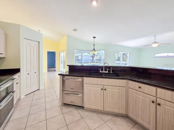 a large kitchen with granite countertop a sink and white cabinets