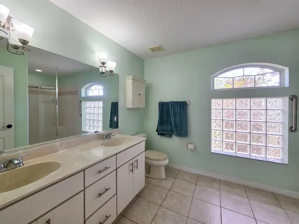 a spacious bathroom with a granite countertop sink a toilet a mirror and a shower