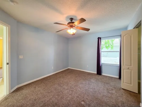 an empty room with windows and fan