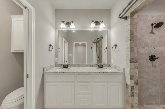 a bathroom with a granite countertop sink a toilet a mirror and shower