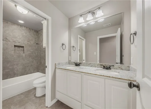 a bathroom with a granite countertop sink a toilet and a large mirror