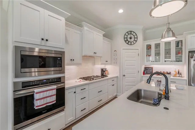 a room with stainless steel appliances kitchen island a white table chairs and a large window