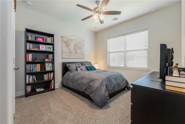 a spacious bedroom with a bed a dresser and a book shelf