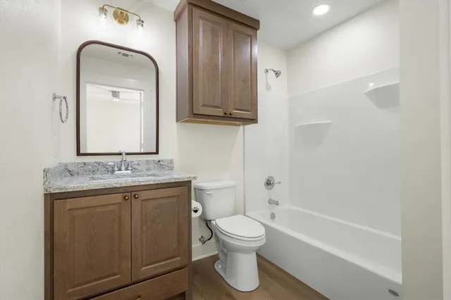 a bathroom with a granite countertop toilet a sink and a mirror