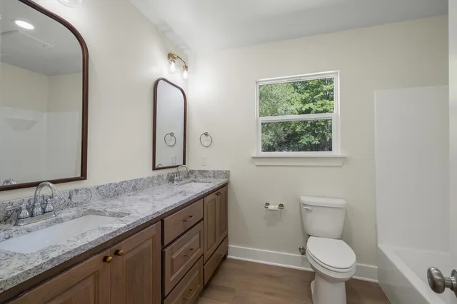 a bathroom with a granite countertop toilet sink and mirror