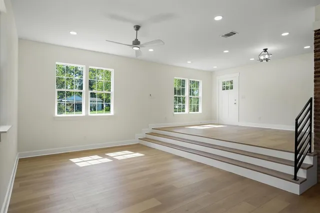 a view of empty room with wooden floor and fan