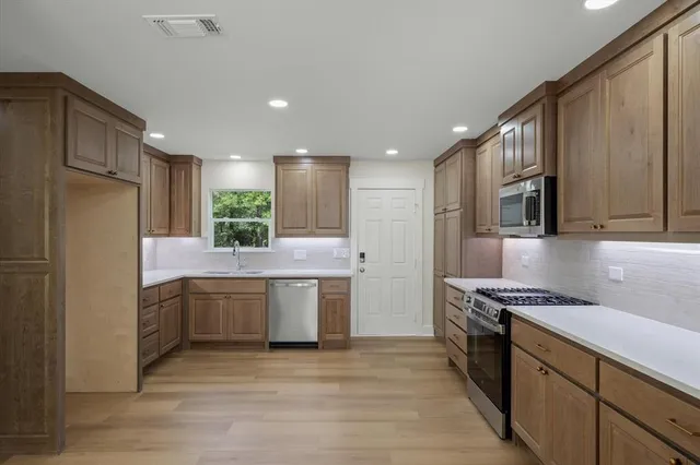 a kitchen with stainless steel appliances granite countertop a sink refrigerator and cabinets