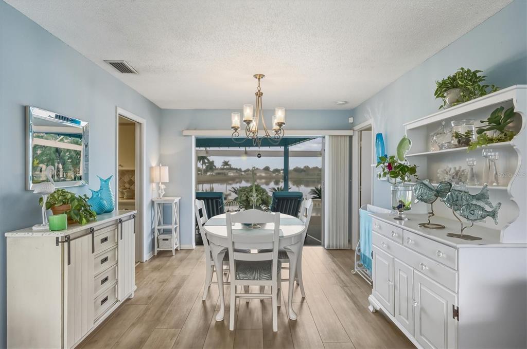 12577 Southwest Kings Row Lake Suzy, FL 34269 - Photo 17 of 56 a dining room with furniture a chandelier and wooden floor