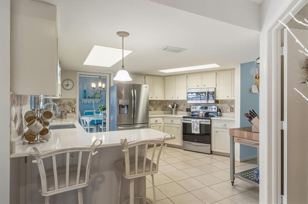 12577 Southwest Kings Row Lake Suzy, FL 34269 - Photo 18 of 56 a kitchen with stainless steel appliances kitchen island granite countertop a dining table chairs and a refrigerator