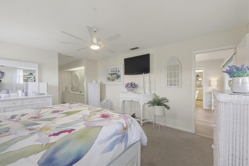 12577 Southwest Kings Row Lake Suzy, FL 34269 - Photo 24 of 56 a spacious bedroom with a bed and a flat screen tv
