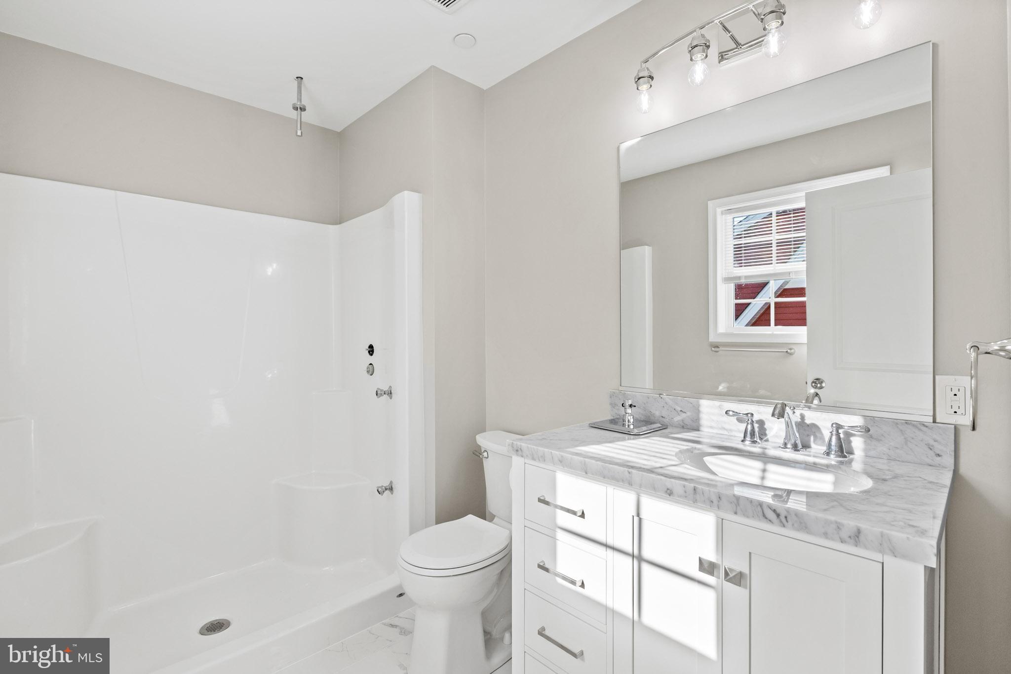 41577 Church Street Leonardtown, MD 20650 - Photo 22 of 25 a bathroom with a granite countertop sink a toilet and shower