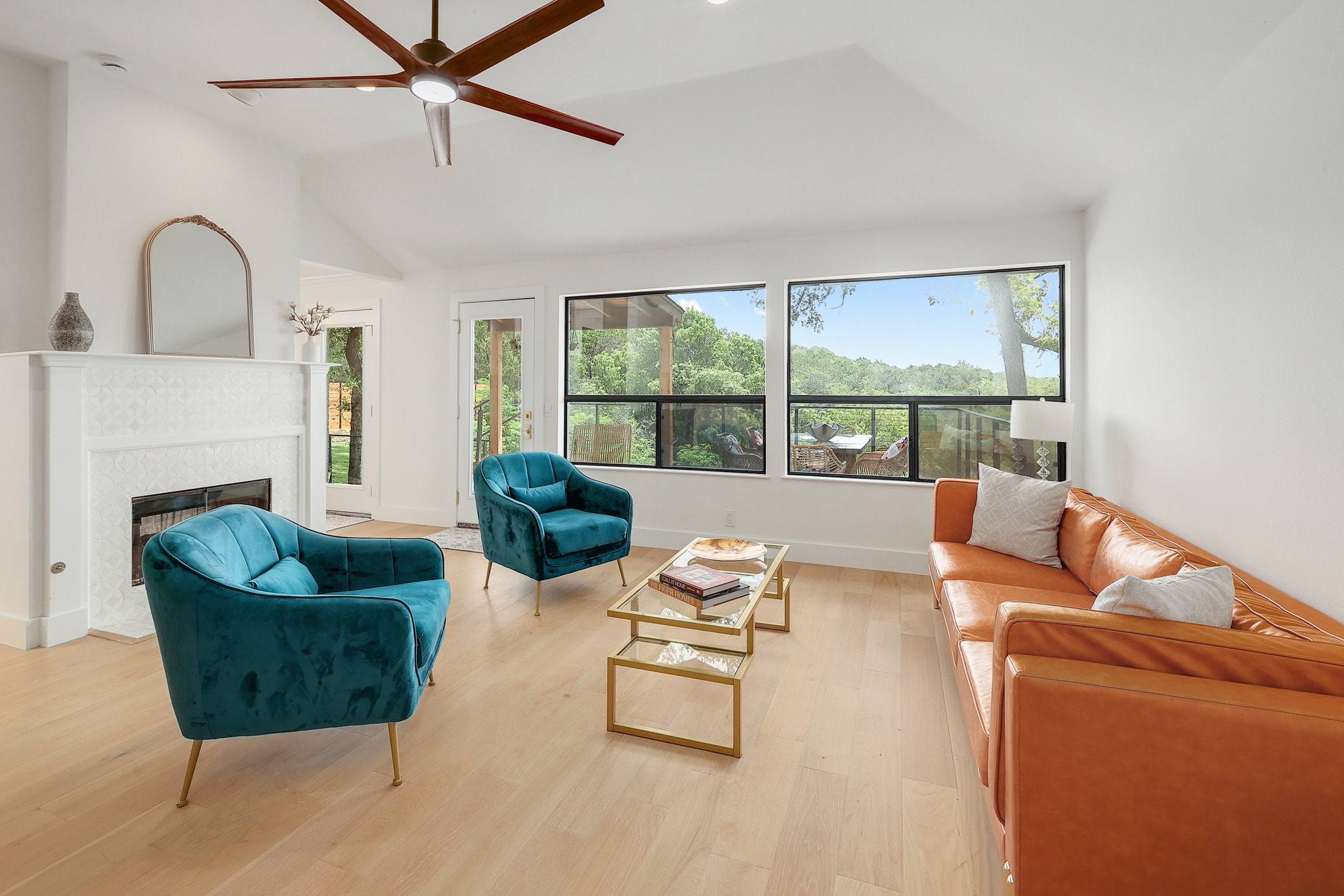 7705 Jester Boulevard Austin, TX 78730 - Photo 12 of 36 A vibrant living area with high ceilings and a fireplace offers serene views of lush greenery.