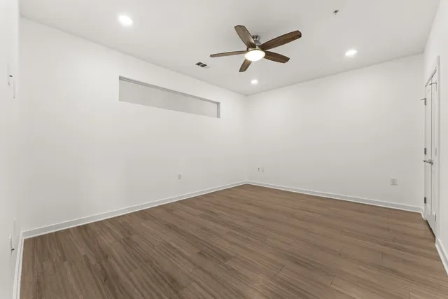 an empty room with wooden floor and windows