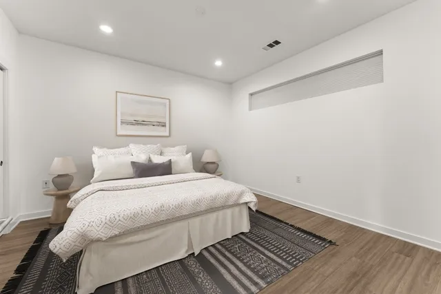 a spacious bedroom with a bed and wooden floor