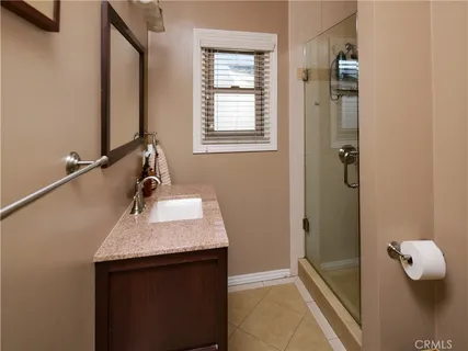a bathroom with a granite countertop sink a mirror and shower