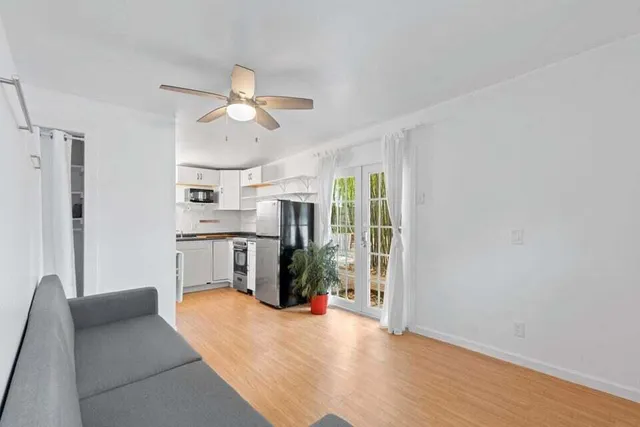 a living room with stainless steel appliances furniture a chandelier and a kitchen view